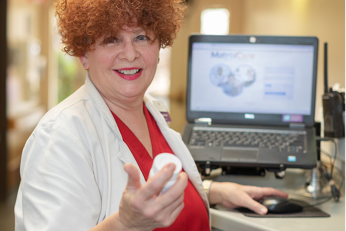 A caregiver at a nurse's cart in the hallway at Crystal Ridge Care Center