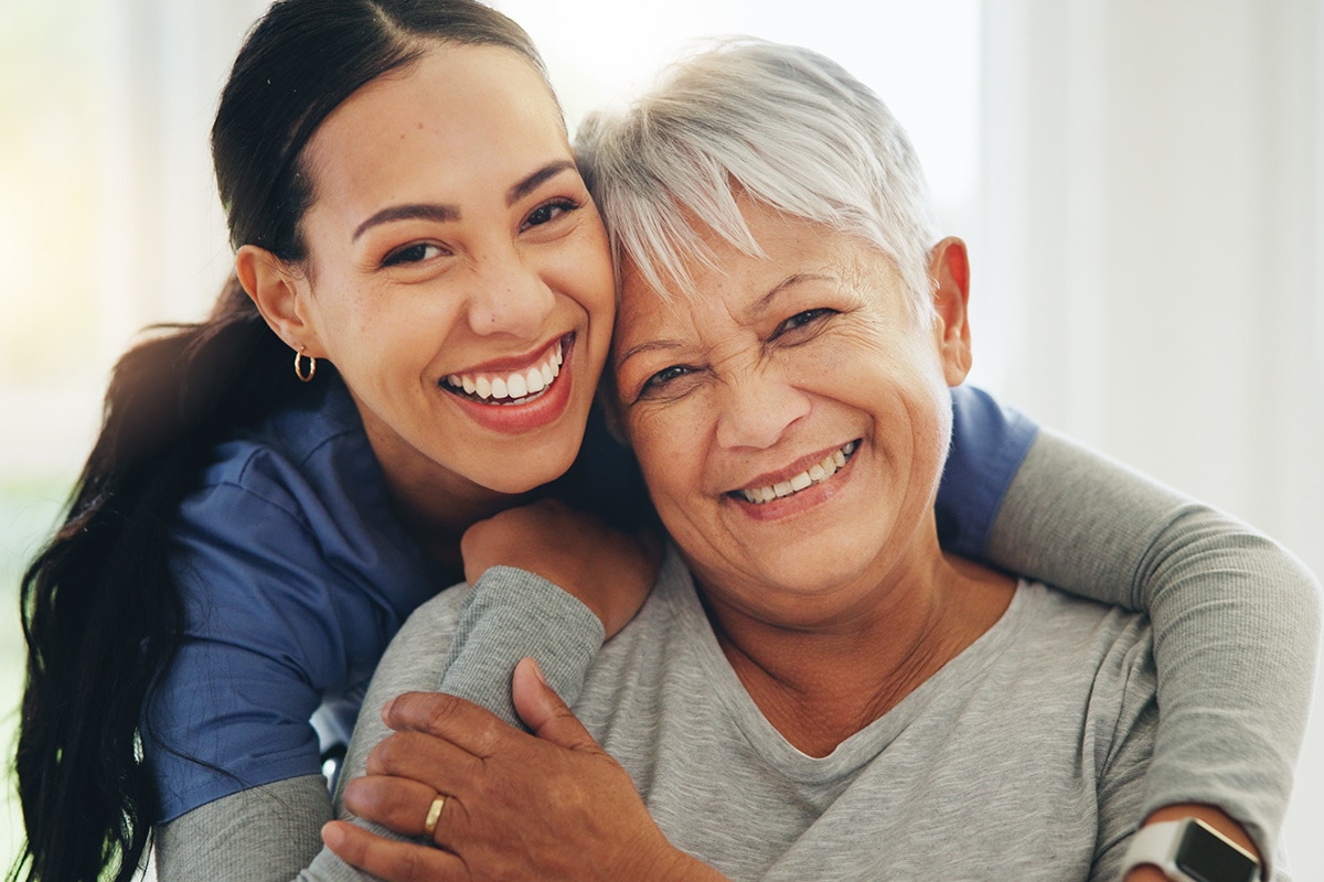 PACS-300x200-caregiver5 Happy woman, nurse and hug senior patient in elderly care, support or trust at old age home. Portrait of mature female person, doctor or medical caregiver hugging with smile for embrace at house